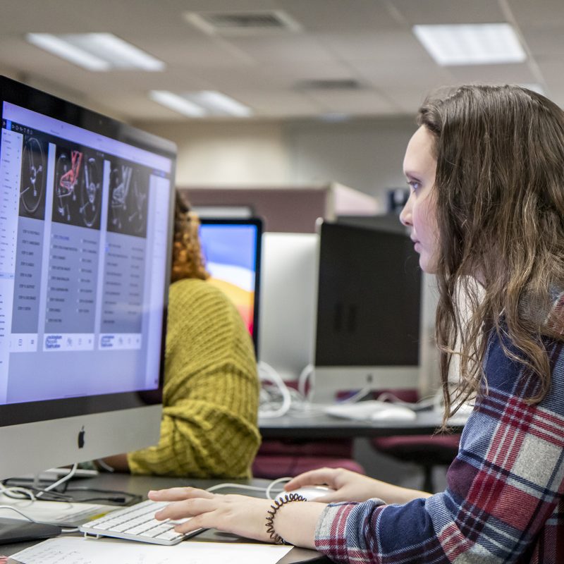 Female student working on digital marketing plan on Mac desktop